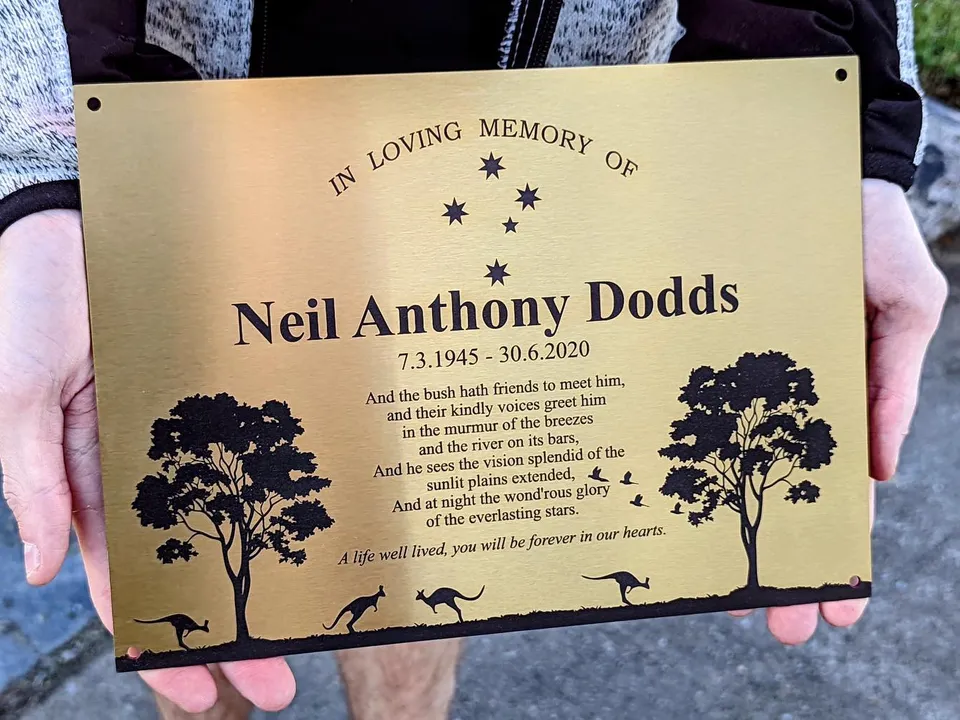 Gold memorial plaque with a verse and an Australian bush scene