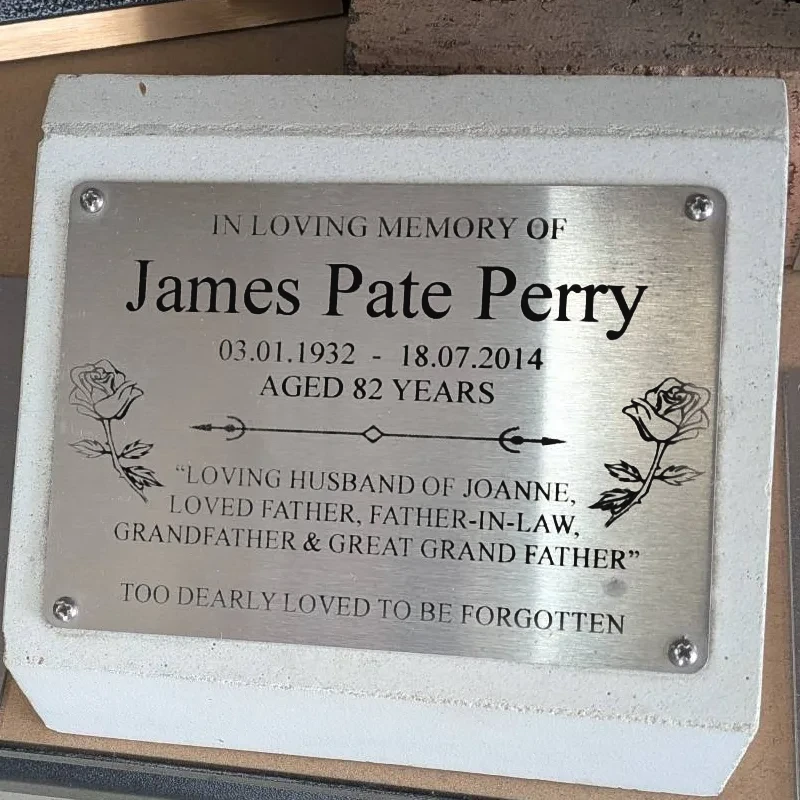 Stainless steel memorial plaque with roses, screwed to a concrete block